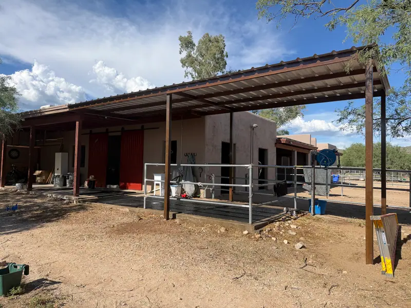 Long steel shade roof with a corrugated metal top over the wash rack of a horse barn